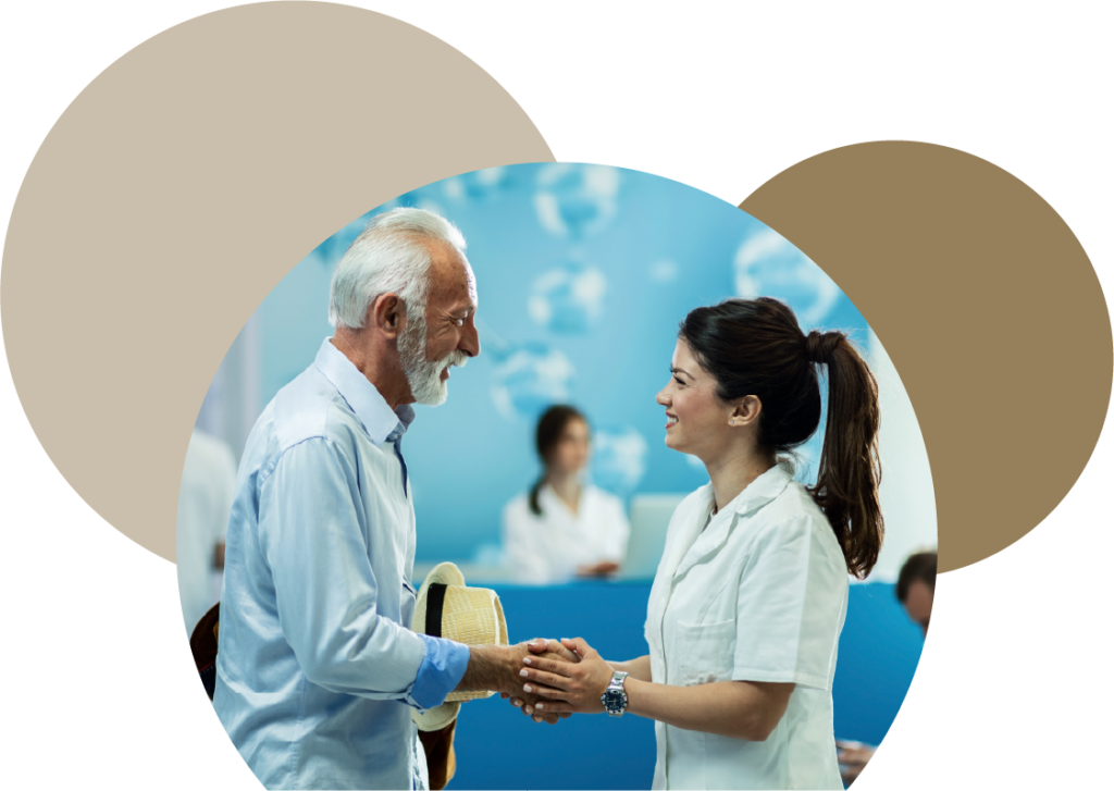 A welcoming medical receptionist smiling and shaking hands with a senior male patient at the clinic reception of Posada Vida Health foundation.